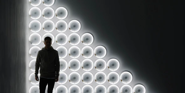 Mann steht vor einer Wand, die mit runden LED-Lichtern beleuchtet wird.