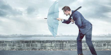 Ein Business Man stemmt bei Regenfall seinen Regenschirm gegen den Wind
