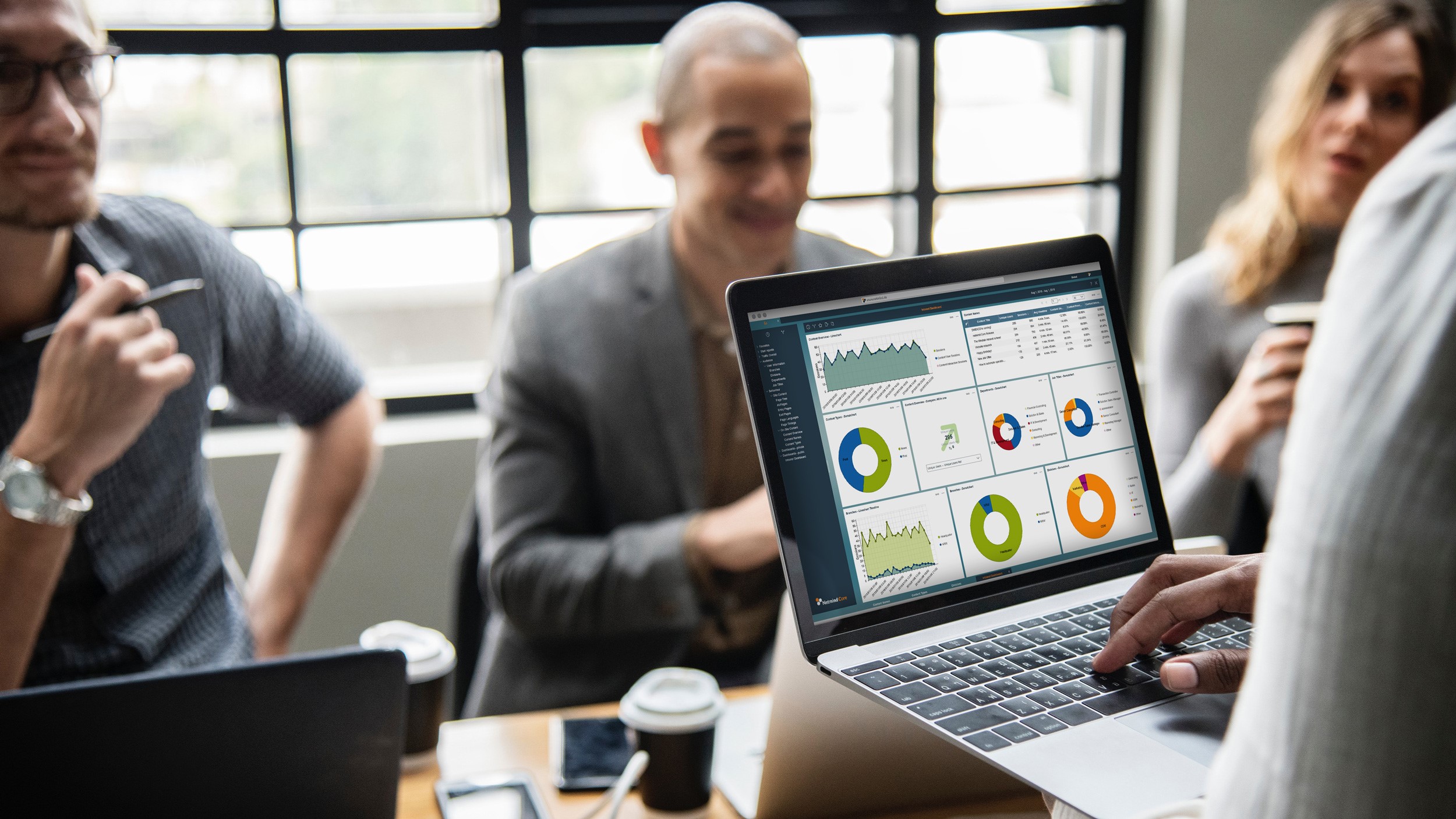 Ein Laptop auf dem ein Dashboard zu sehen ist wird bedient, dahinter sitzt ein Mann