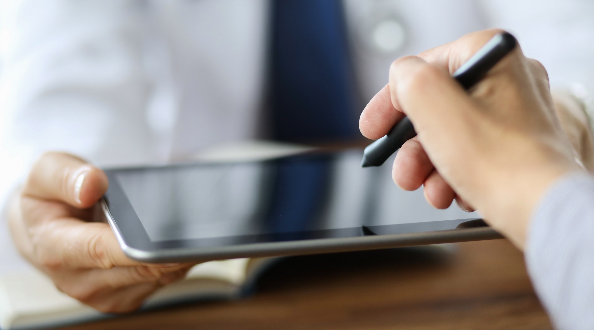 Eine Hand hält einen Stift für eine elektronische Unterschrift auf einem Tablet