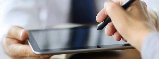 Eine Hand hält einen Stift für eine elektronische Unterschrift auf einem Tablet