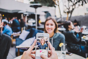 Eine Hand hält ein Handy, das gerade ein Mädchen in einem Restaurant fotografiert