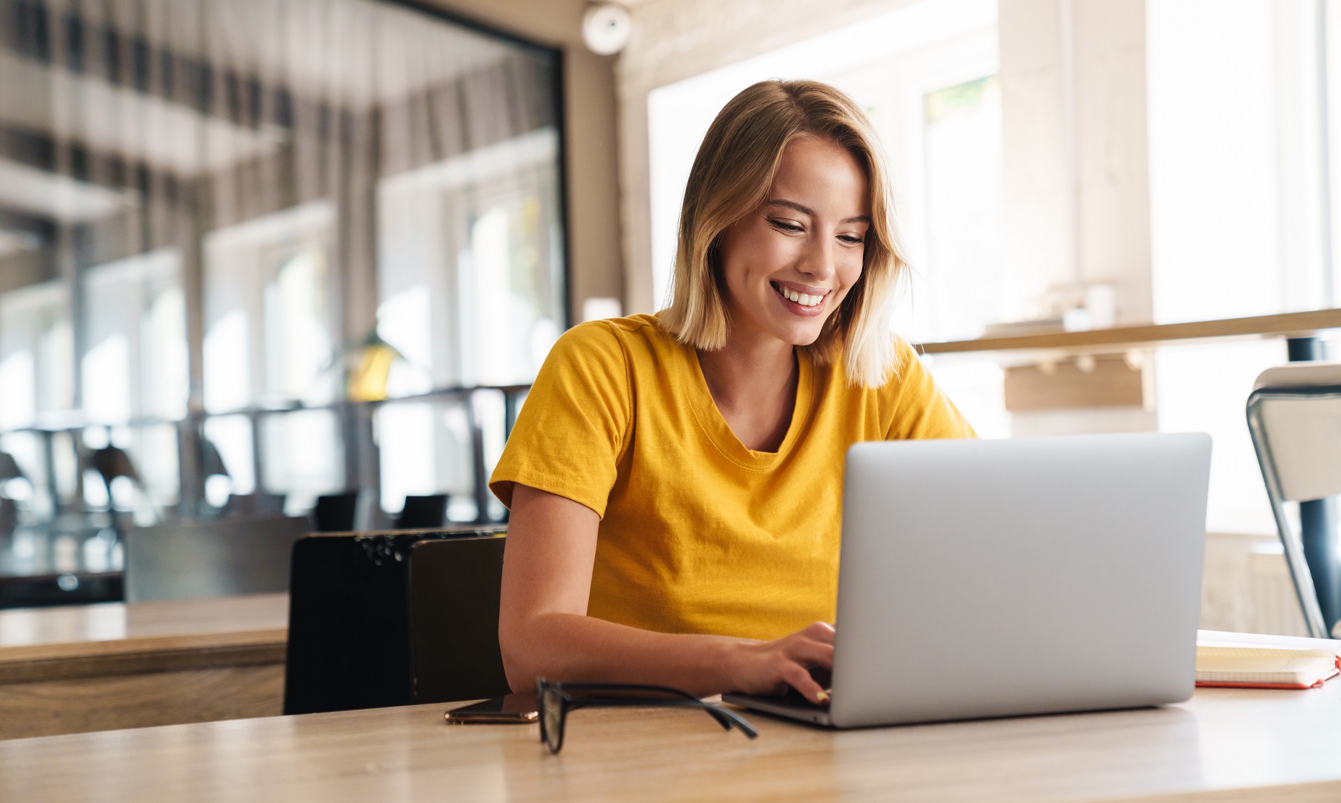 Eine lächelnde Frau sitzt vor einem Laptop