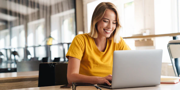 Eine lächelnde Frau sitzt vor einem Laptop