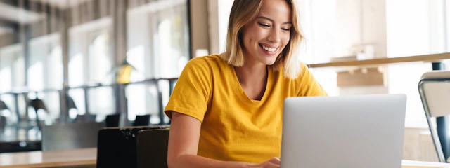 Eine lächelnde Frau sitzt vor einem Laptop