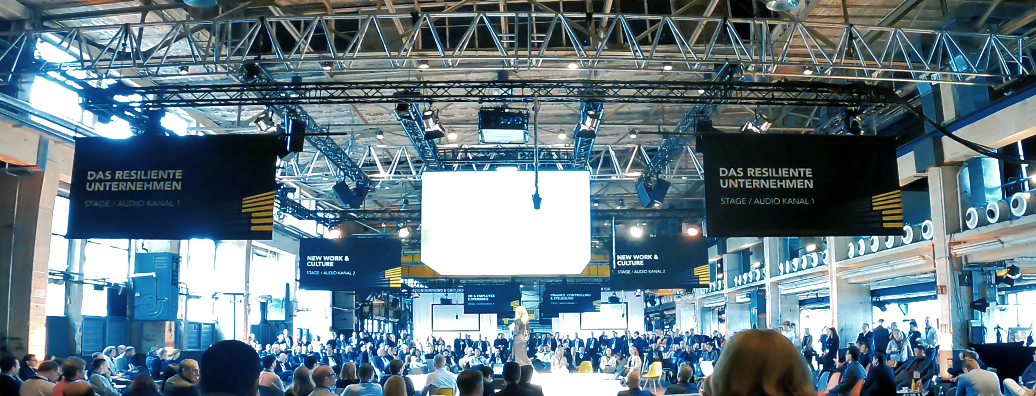 Eine Event mit zahlreichen Menschen und einer großen Leinwand