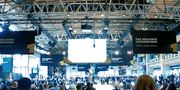 Eine Event mit zahlreichen Menschen und einer großen Leinwand