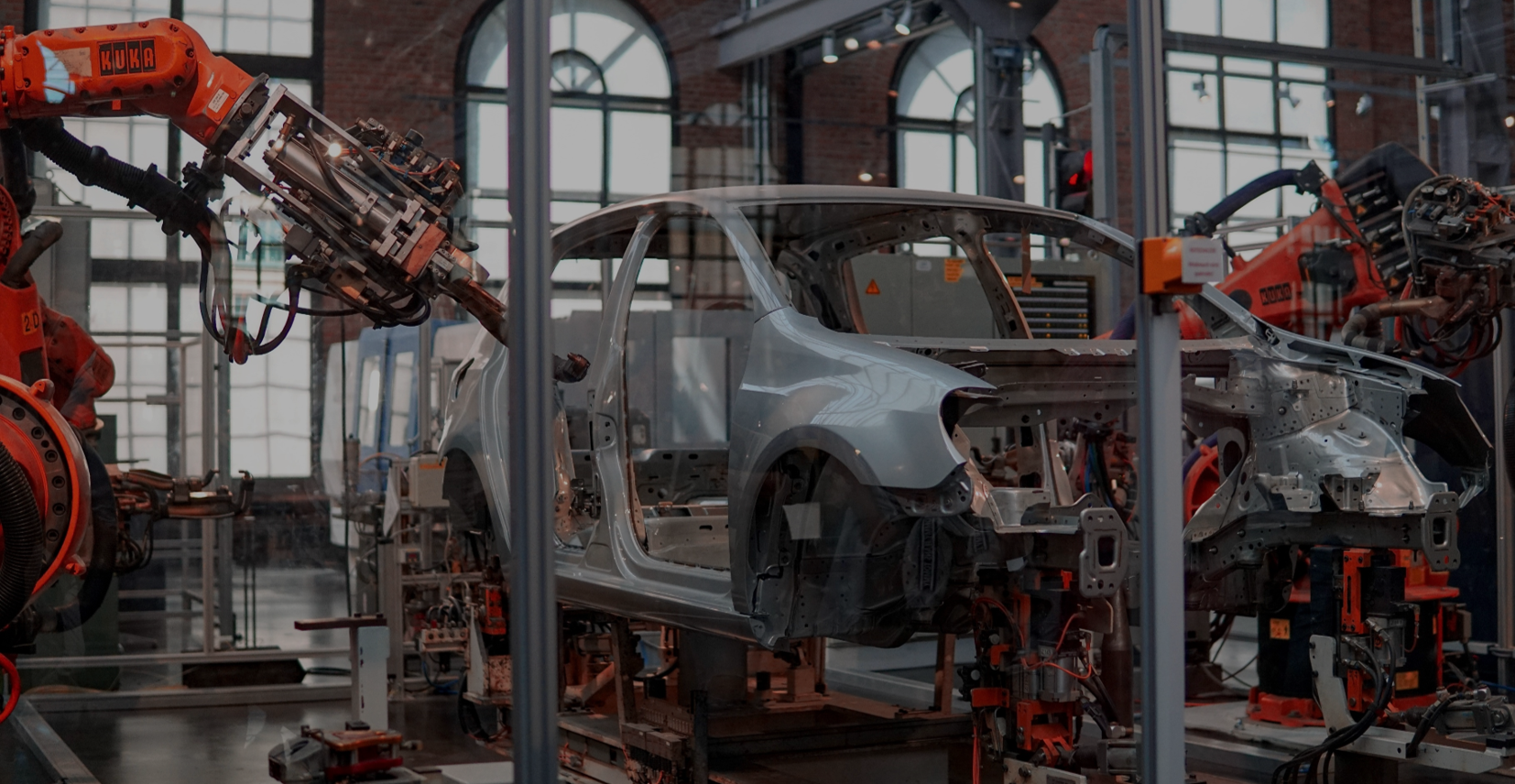 Ein Ausschnitt einer Automobilproduktion, bei dem eine Karosserie von Roboterarmen bearbeitet wird