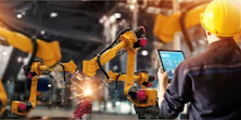 Ein Werksarbeiter hält ein Tablet in einer modernen Fabrik mit Robotern