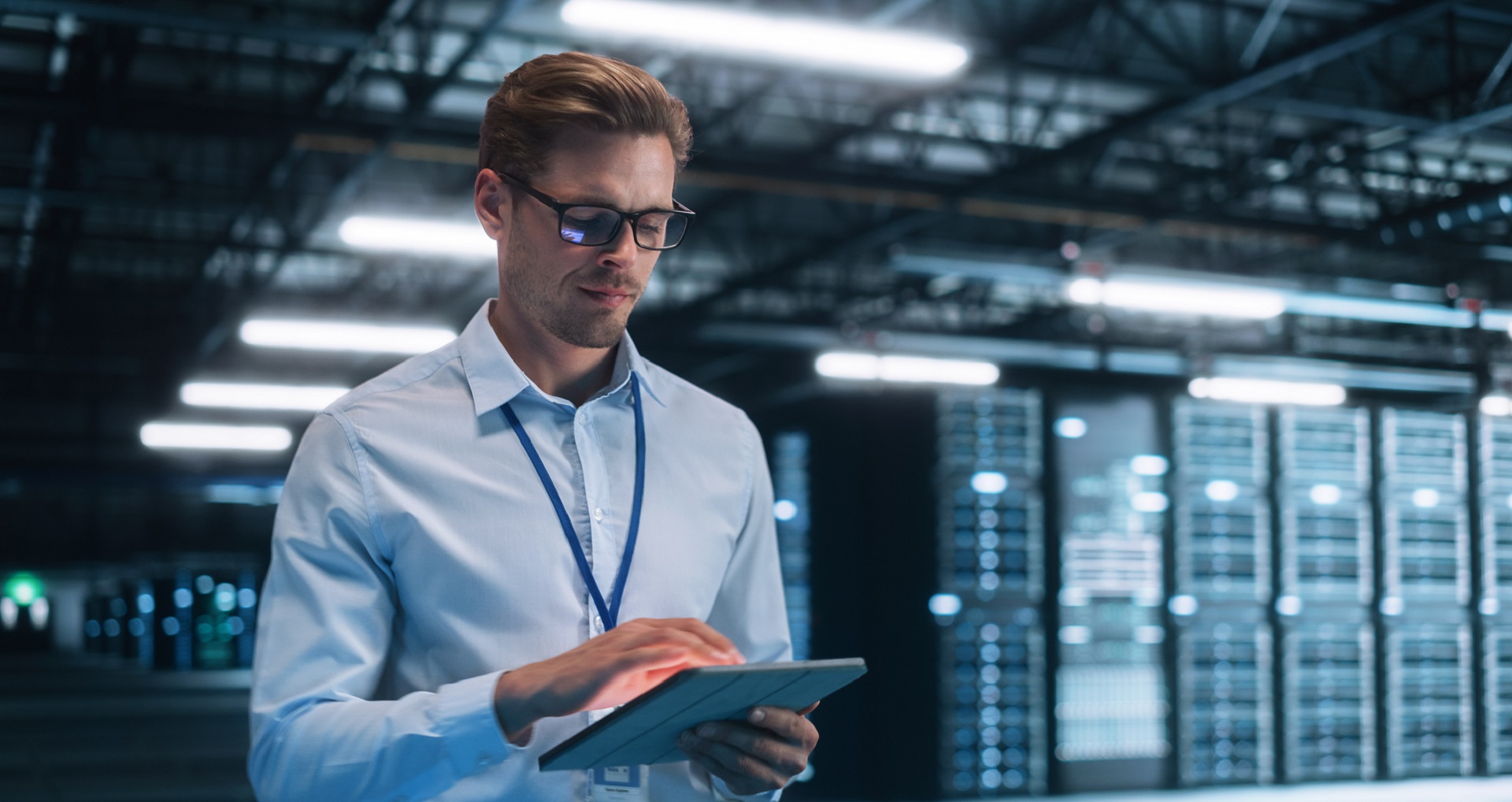 Ein Mann hält ein Tablet in einem Serverraum