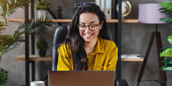 Eine Frau lächelt vor einem Laptop
