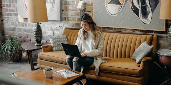 Eine Frau sitzt mit ihrem Laptop auf einer Couch