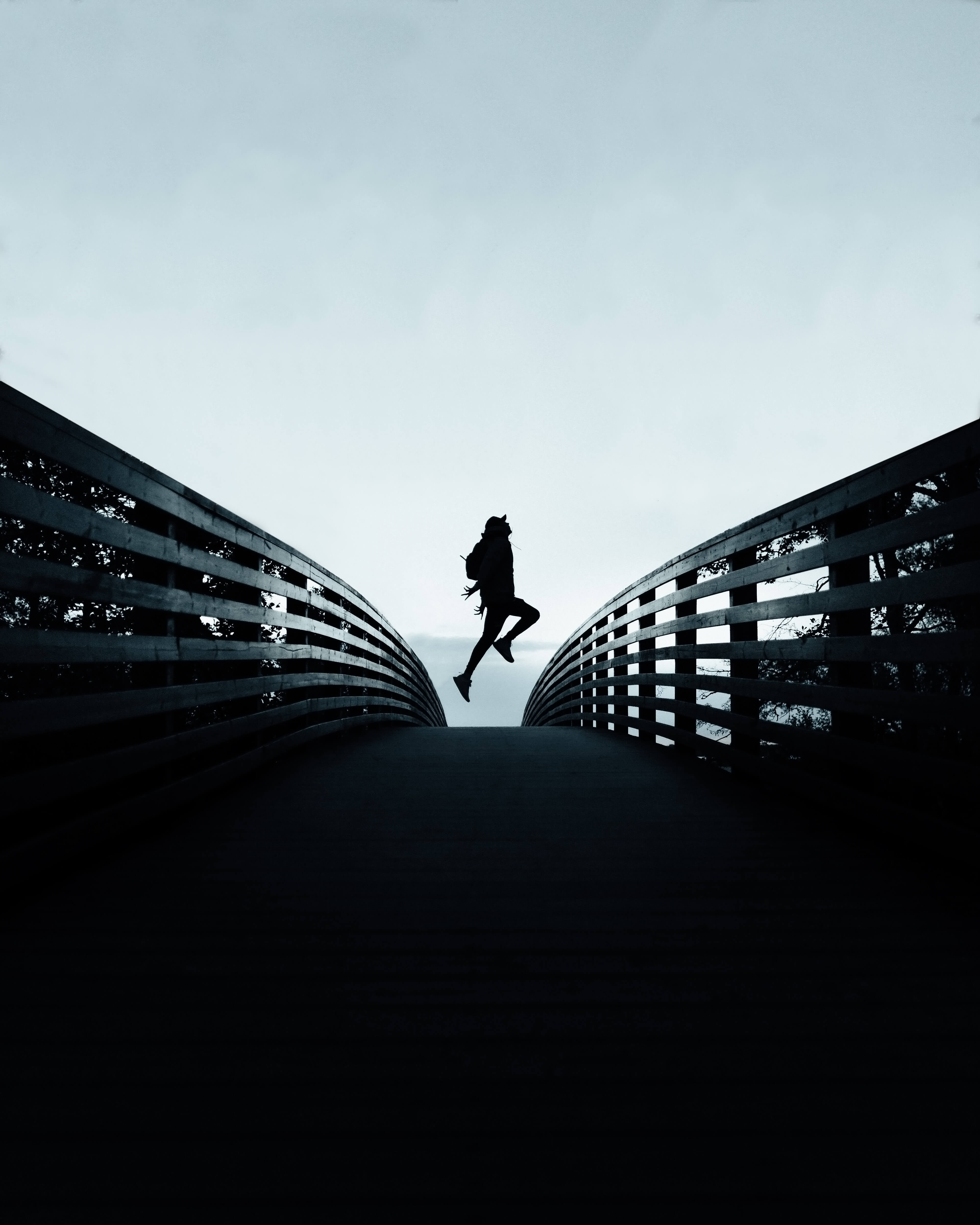 Ein Mensch, der mitten auf einer Brücke hochspringt