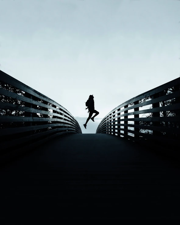 Ein Mensch, der mitten auf einer Brücke hochspringt