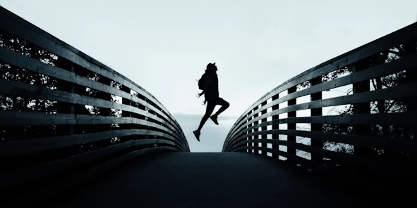 Ein Mensch, der mitten auf einer Brücke hochspringt