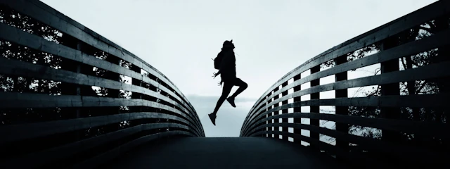 Ein Mensch, der mitten auf einer Brücke hochspringt