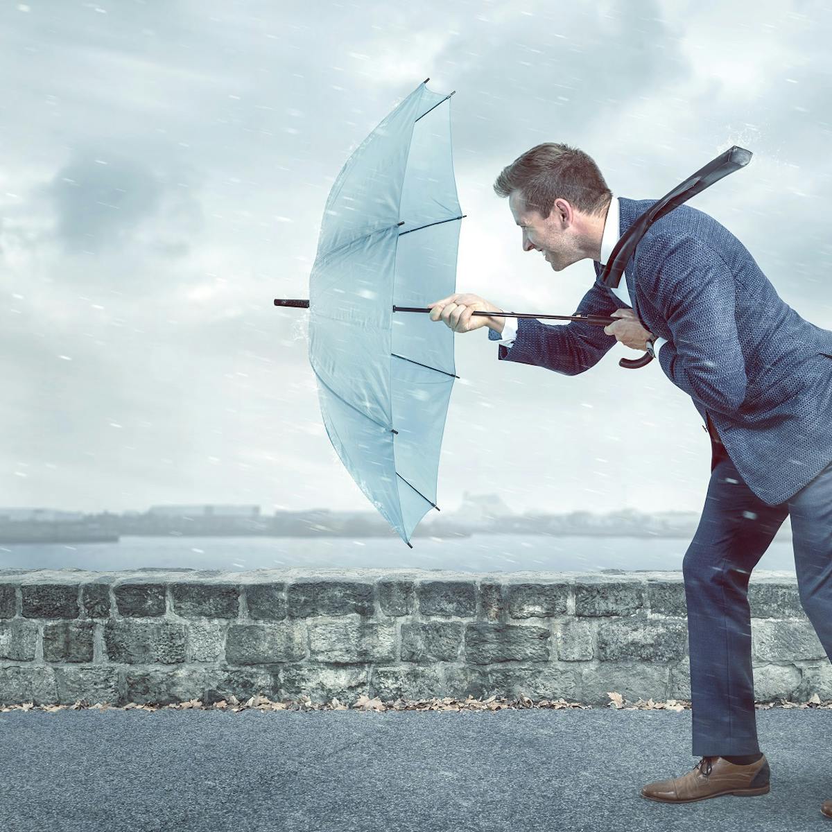 Mann stemmt sich mit Regenschirm gegen Regen