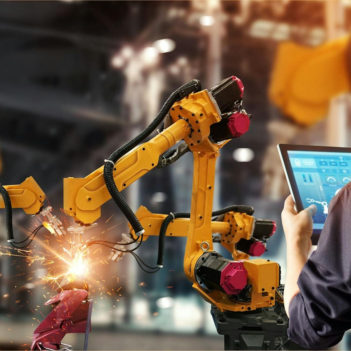 Arbeiter steuert Roboter mit Tablet