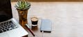 Auf einem Tisch liegen ein Laptop, ein Kugelschreiber, eine Tasse Kaffee und ein Smartphone